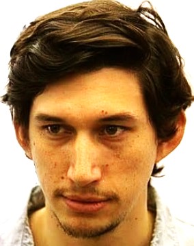 Close-up of a young man with dark brown hair and light facial stubble, looking downward with a thoughtful expression.